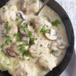 chicken meatballs in mushroom sauce in a black bowl with a spoon.