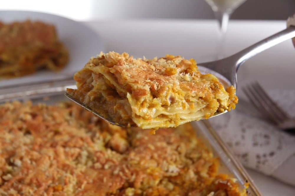 curried chicken lasagna with pumpkin slice being lifted from the dish.