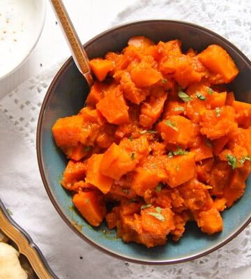 braised pumpkin with spices in a blue bowl with yogurt