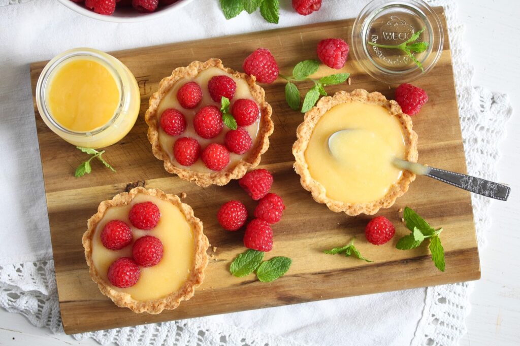 fresh raspberry tarts with lemon being assembled on a wooden board