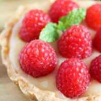 one tart with lemon filling and jewel like raspberries on top