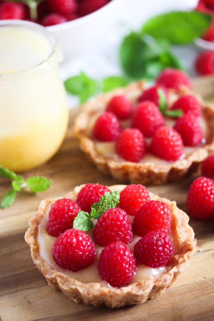 jar of lemon curd and raspberry tarts on the table