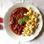 vegan seitan stew with pasta on a white plate