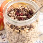 homemade muesli mix in a large jars with bananas behind