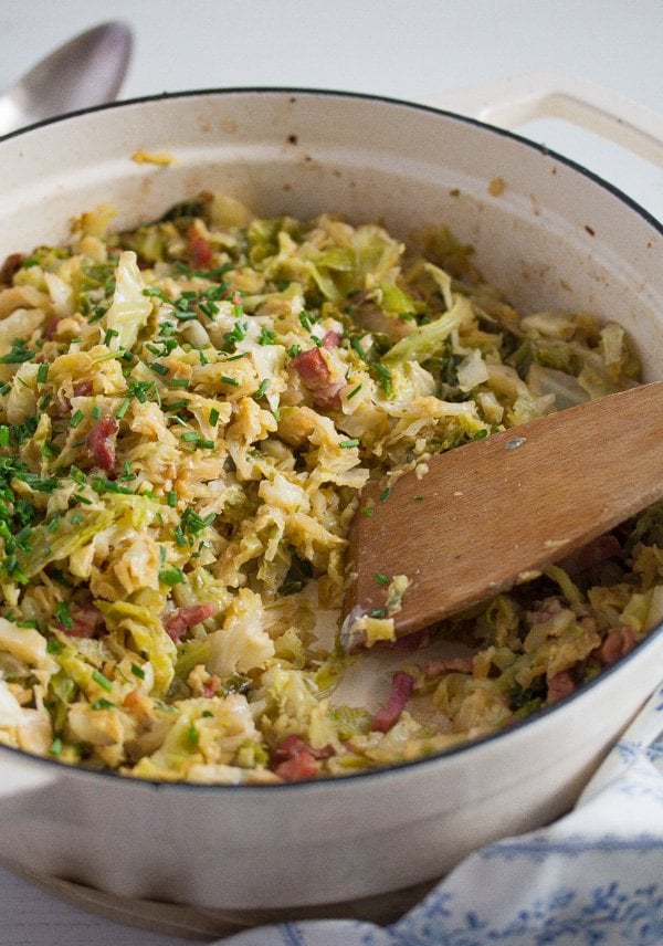 sauteed savoy cabbage and bacon in a skillet with a wooden spoon