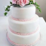 three-tiered wedding cake with fondant roses on top.