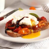 runny poached egg on sourdough with tomatoes