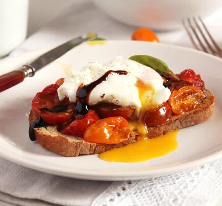 runny poached egg on sourdough with tomatoes