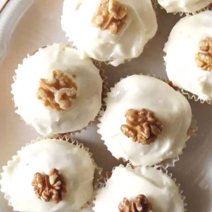 carrot cake muffins frosted and decorated with walnuts close up.