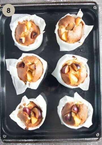 freshly baked plums clafoutis in ramekin dishes on a baking sheet.