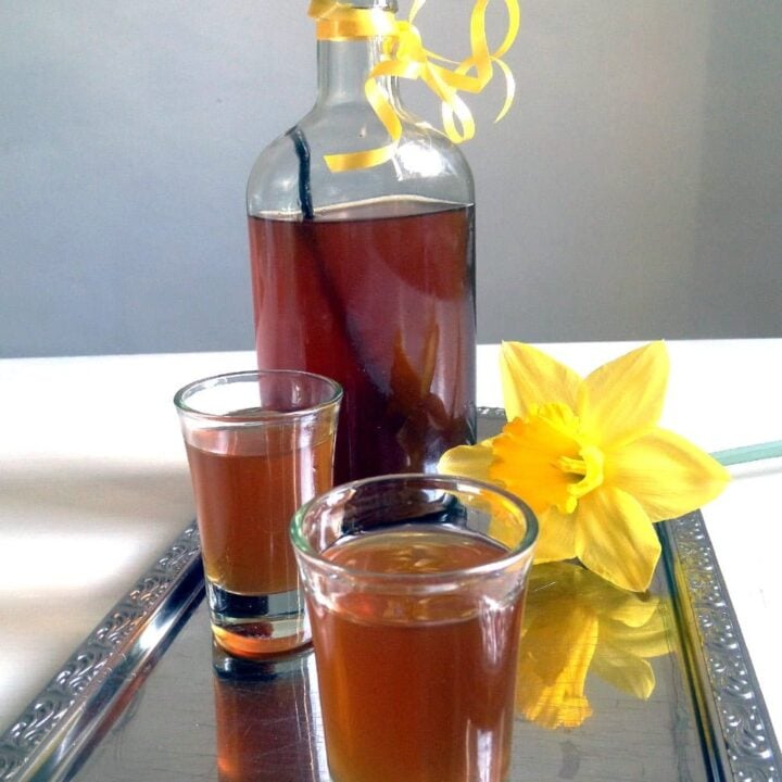 bottle and glasses with honey liqueur on a silver tray