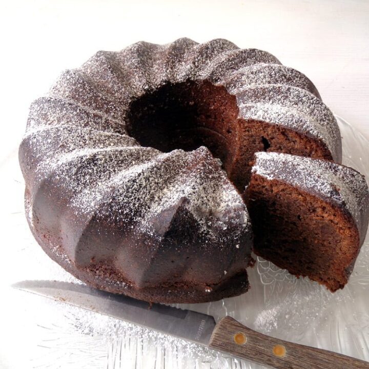 slice bundt cake with chocolate on a platter with a small knife