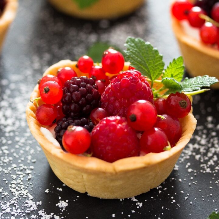 close up mini berry tart on a black table