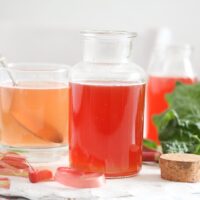 rhubarb peel syrup on the table with leaves behind