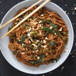 bowl of chinese noodles with brown sauce and spinach.
