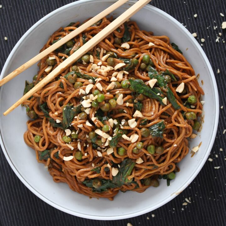 bowl of chinese noodles with brown sauce and spinach
