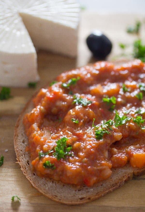 serving red pepper spread on bread with feta and olives.