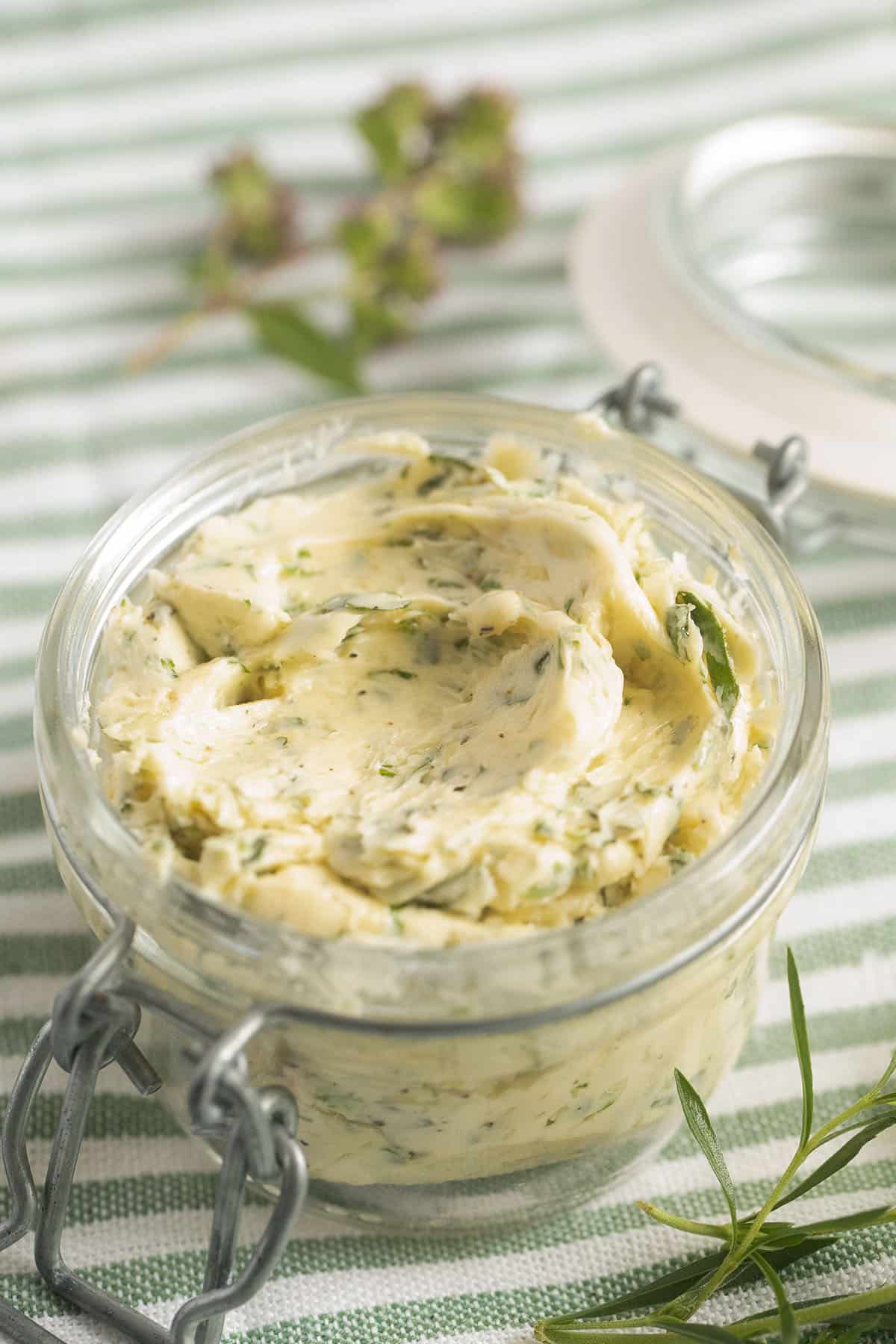 jar of garlic butter with oregano, basil, parsley, and thyme.