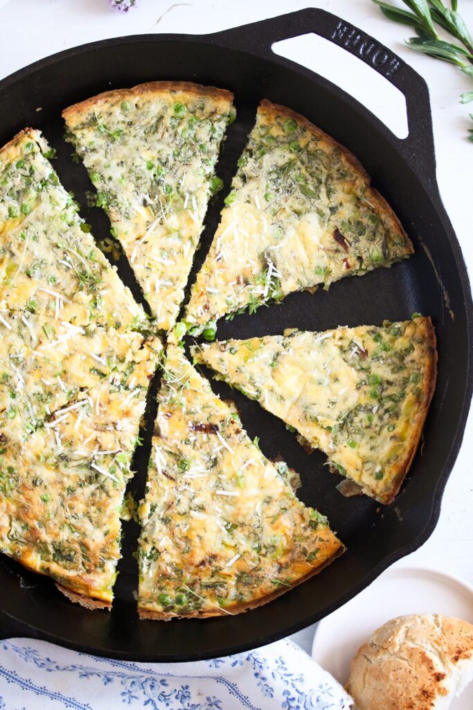 cast iron pan with parmesan frittata cut into wedges