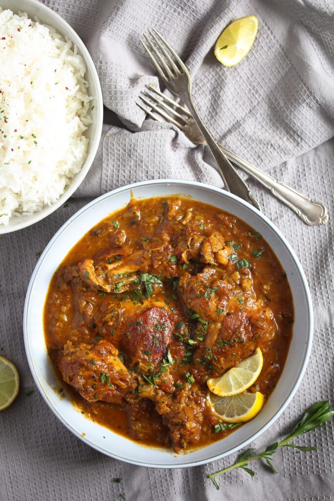 chicken thighs and drumsticks in a red sauce with lemon slices