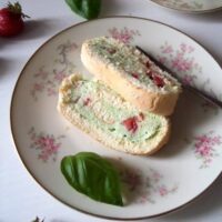 sliced strawberry basil roulade on a plate with basil leaves