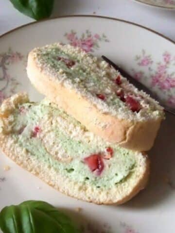 two slices of strawberry basil roll cake on a vintage plate with pink flowers.