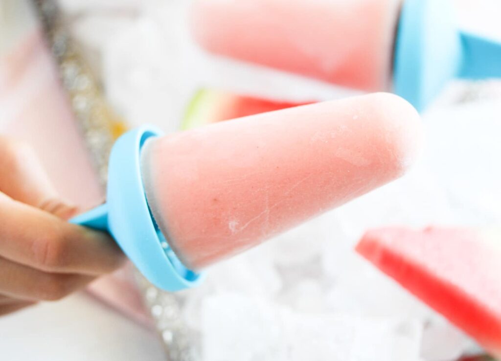 hand holding a pink yogurt popsicle