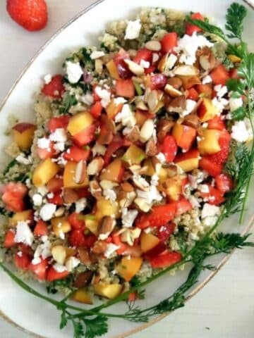summer quinoa salad topped with peaches, nuts and herbs.