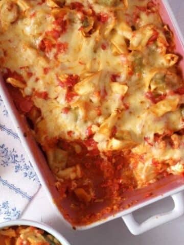 tortellini vegetable bake with cheese on top in a casserole dish.