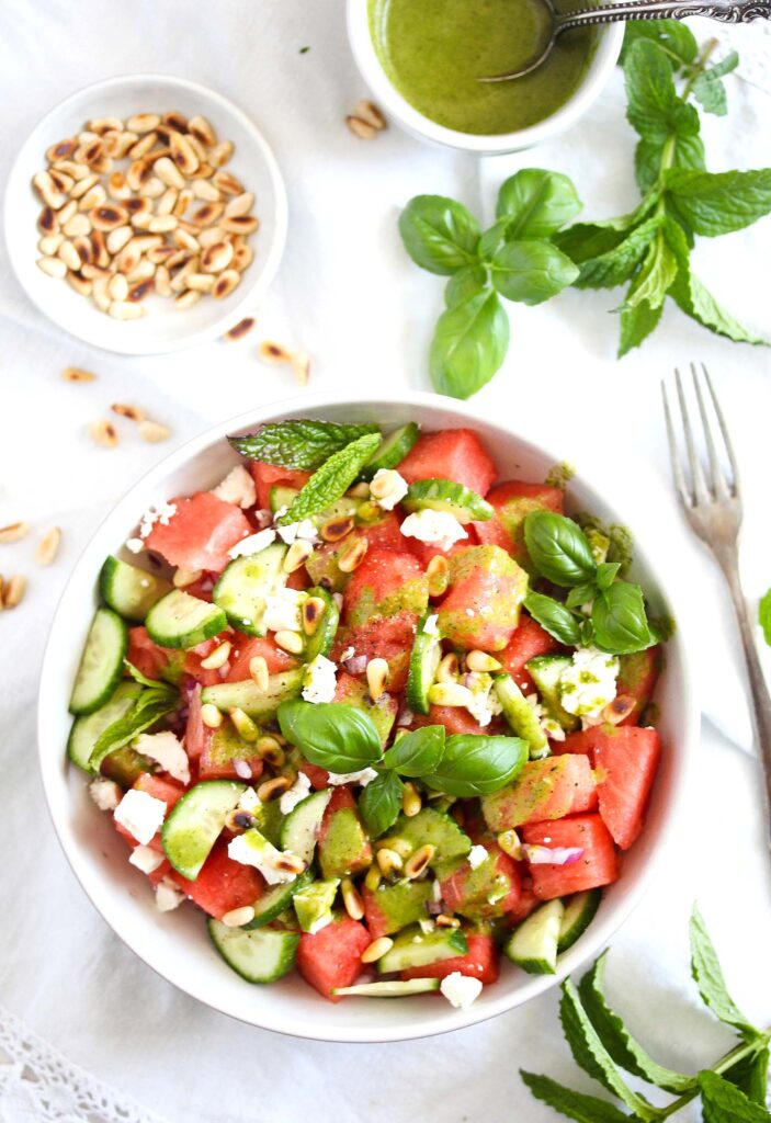 salad with cheese and herbs in a bowl with pine nuts on the side