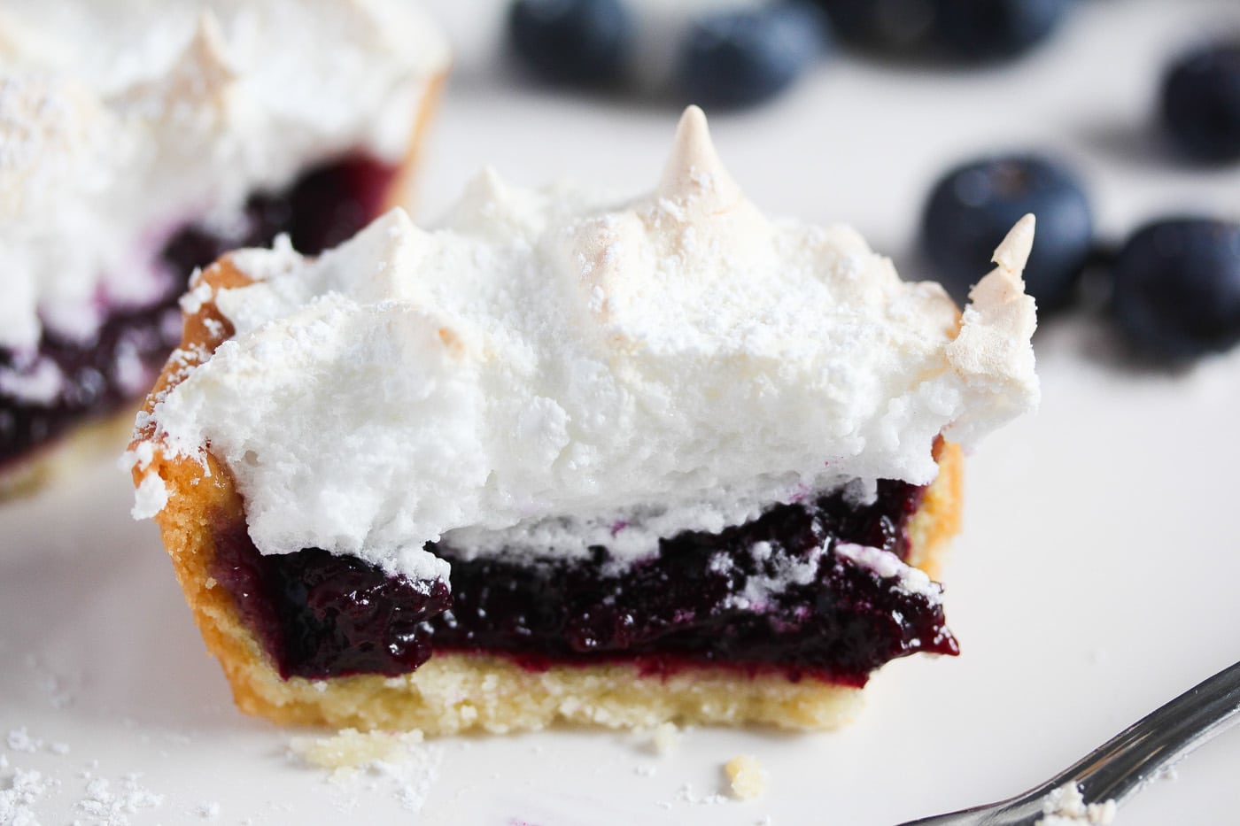 close up of blueberry curd filling in small tart with meringue topping