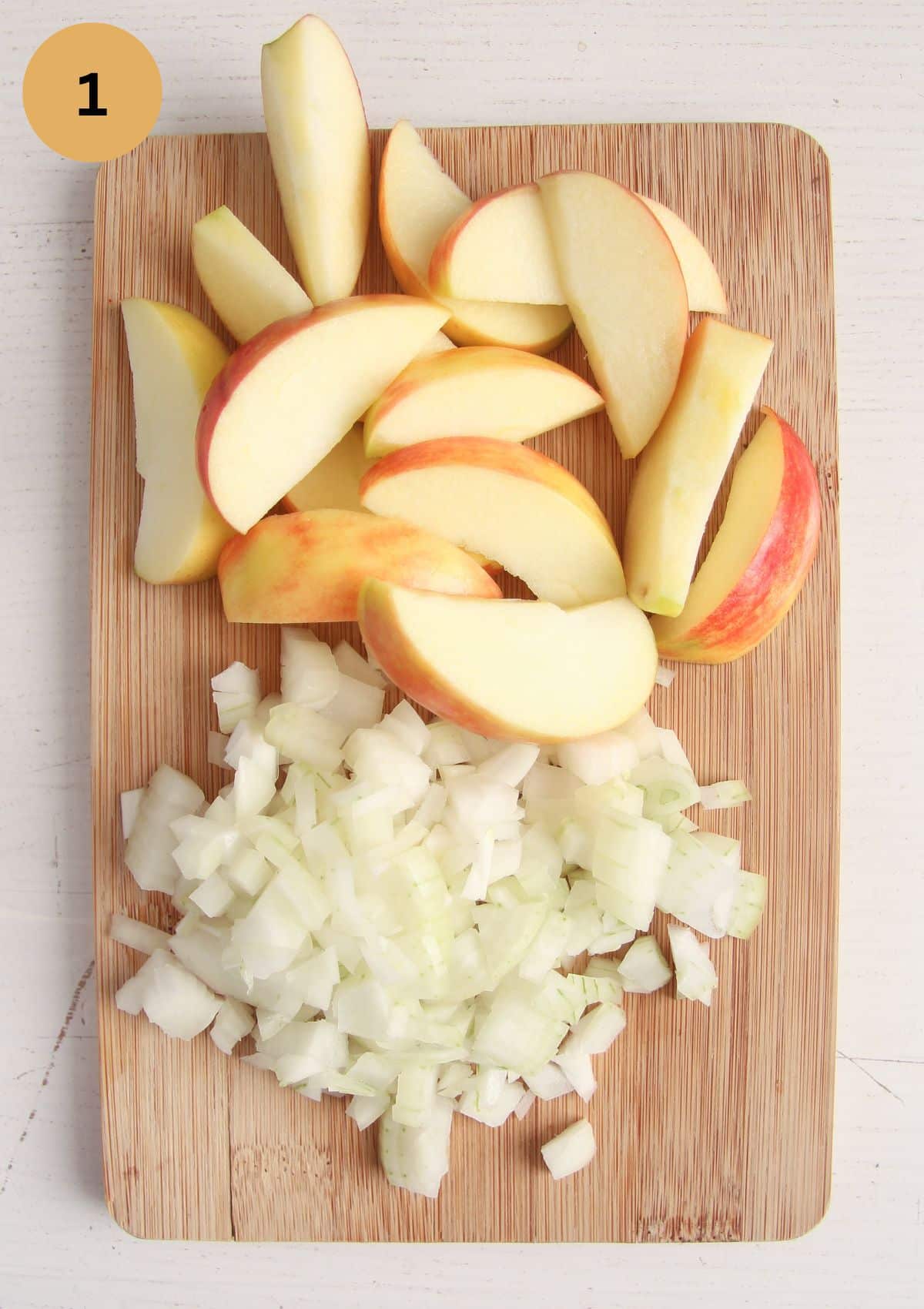 sliced apples and chopped onions on a wooden board.