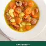 carrot potato sausage soup on a white plate