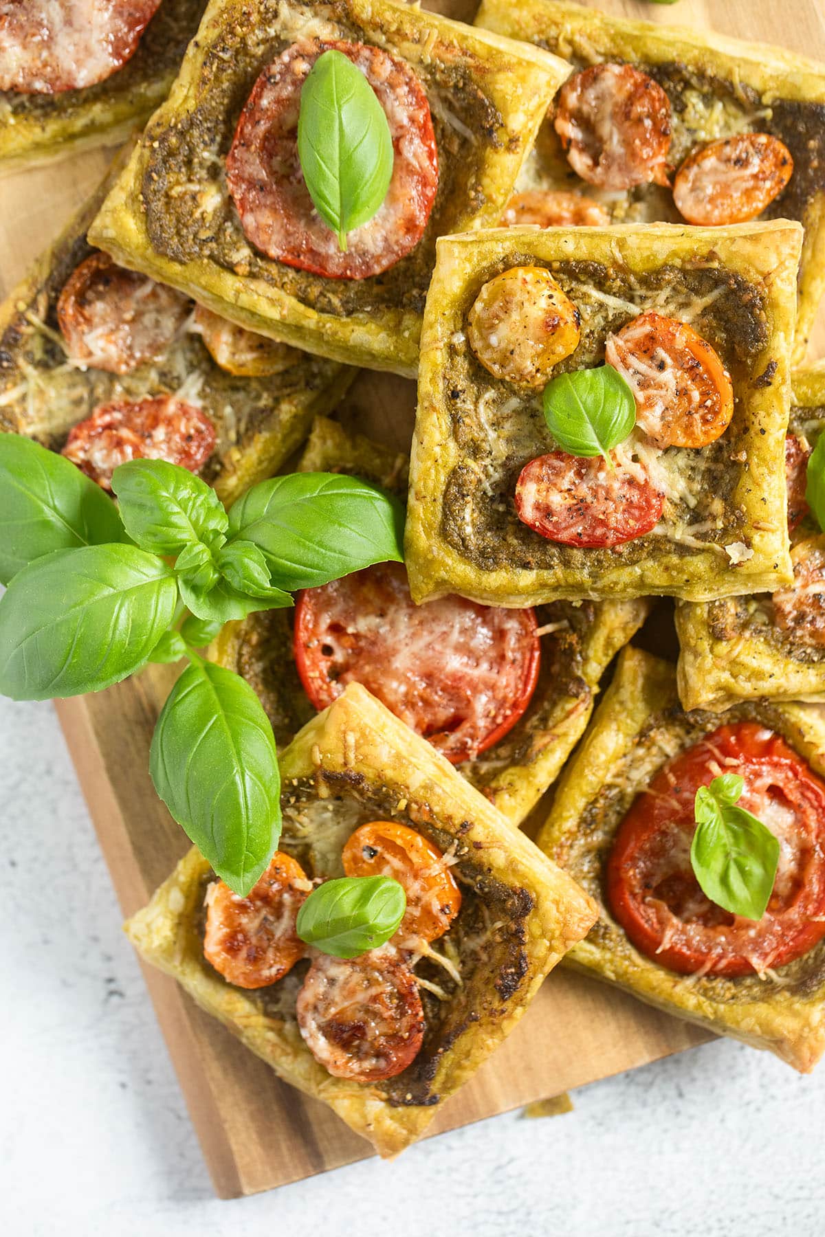 many square puff pastry nibbles topped with pesto, tomatoes and parmesan.