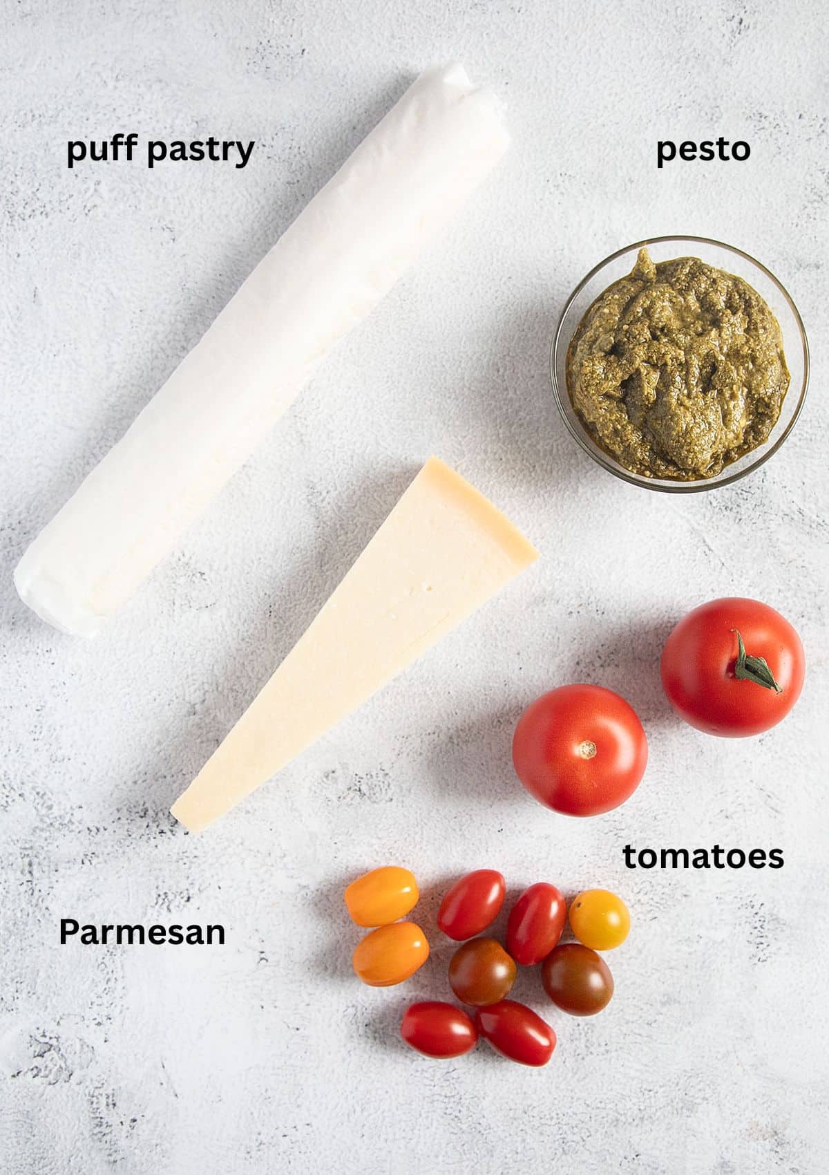 labeled ingredients for making canapes with puff pastry, tomatoes, pesto and parmesan.