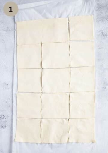 twelve cut squares of puff pastry on parchment paper.