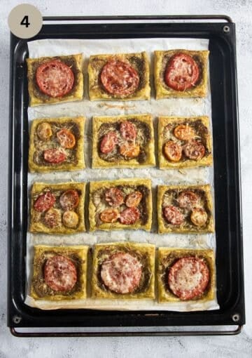 twelve squares of puff pastry with pesto and tomatoes on a baking sheet.