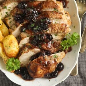 sliced blueberry turkey breast served with golden roasted potatoes and blueberry sauce.