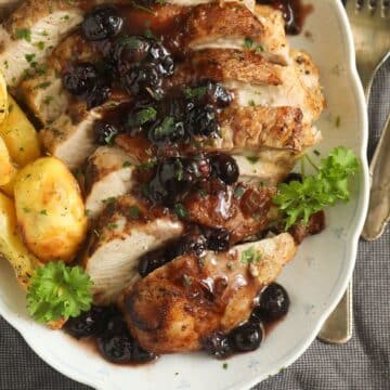 sliced blueberry turkey breast served with golden roasted potatoes and blueberry sauce.