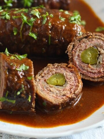plate of sliced meat roulades with lots of sauce and parsley
