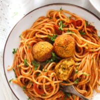 tangled spaghetti with red pepper sauce and chickpea balls on a plate.