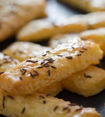many cheese sticks sprinkled with caraway seeds on the table.