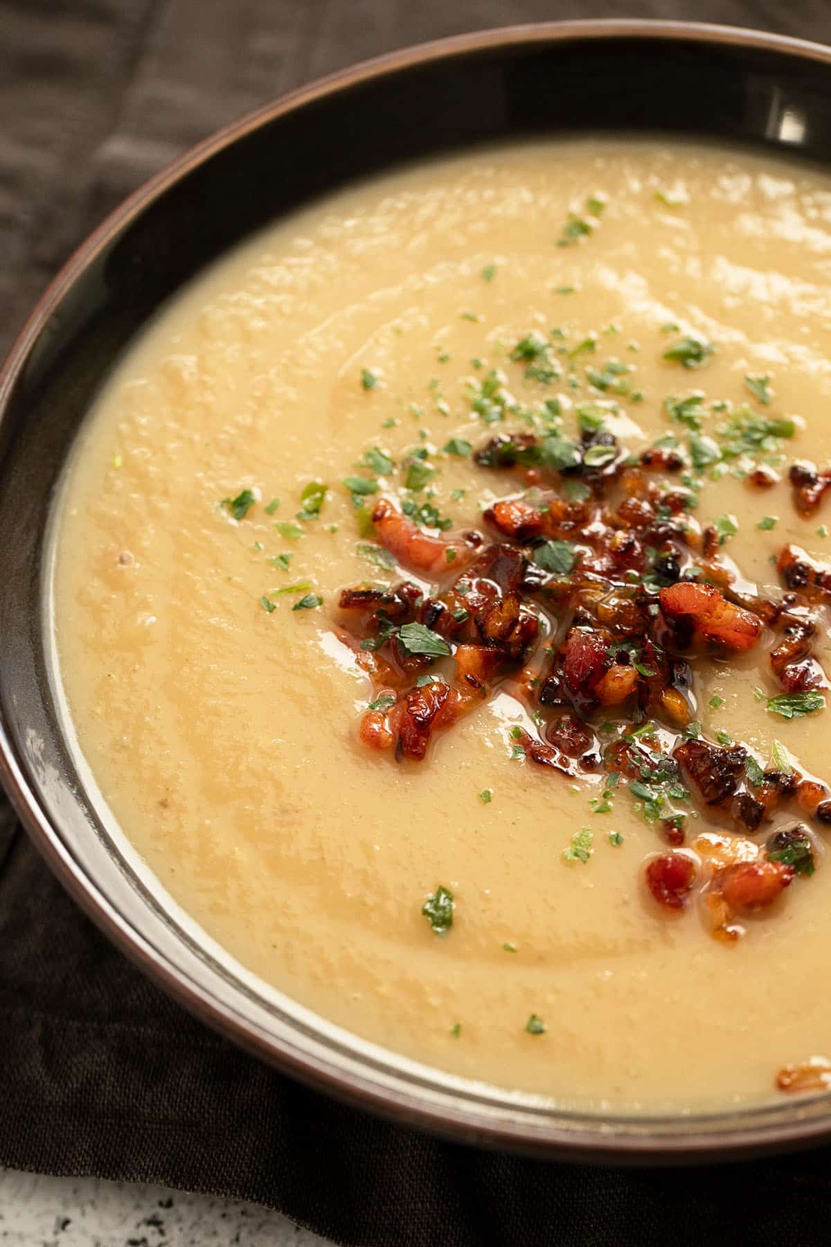 bowl of creamy sunchoke soup with bacon and hot sauce topping.