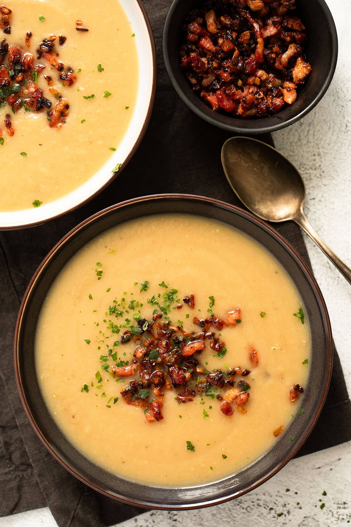 two bowls of sunchoke soup with bacon topping.