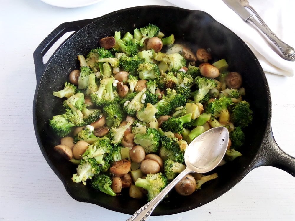 broccoli mushrooms blue cheese in a large cast-iron skillet with a spoon in it.