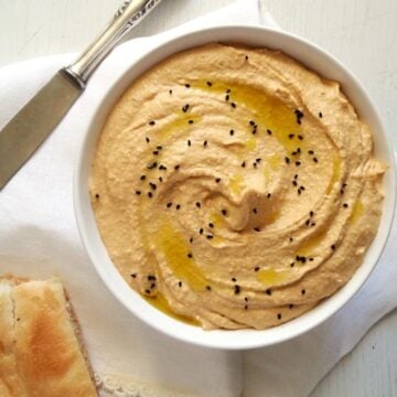 low-calorie hummus in a white bowl with flat bread