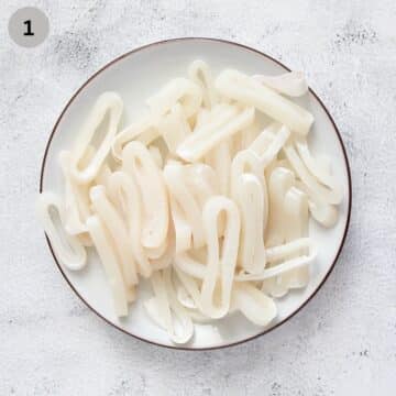 thinly sliced raw calamari rings on a plate.