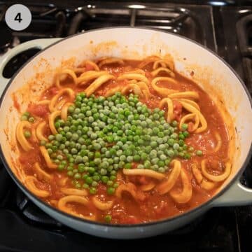 adding frozen peas to tomato and calamari sauce in a pot.