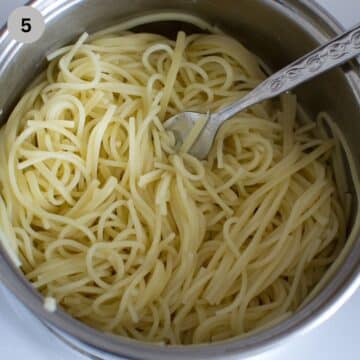 cooked spaghetti and fork in a sieve.