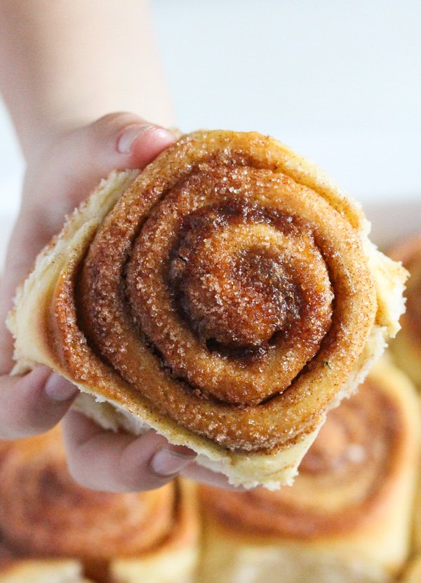 girl holding one sweet roll with cinnamon